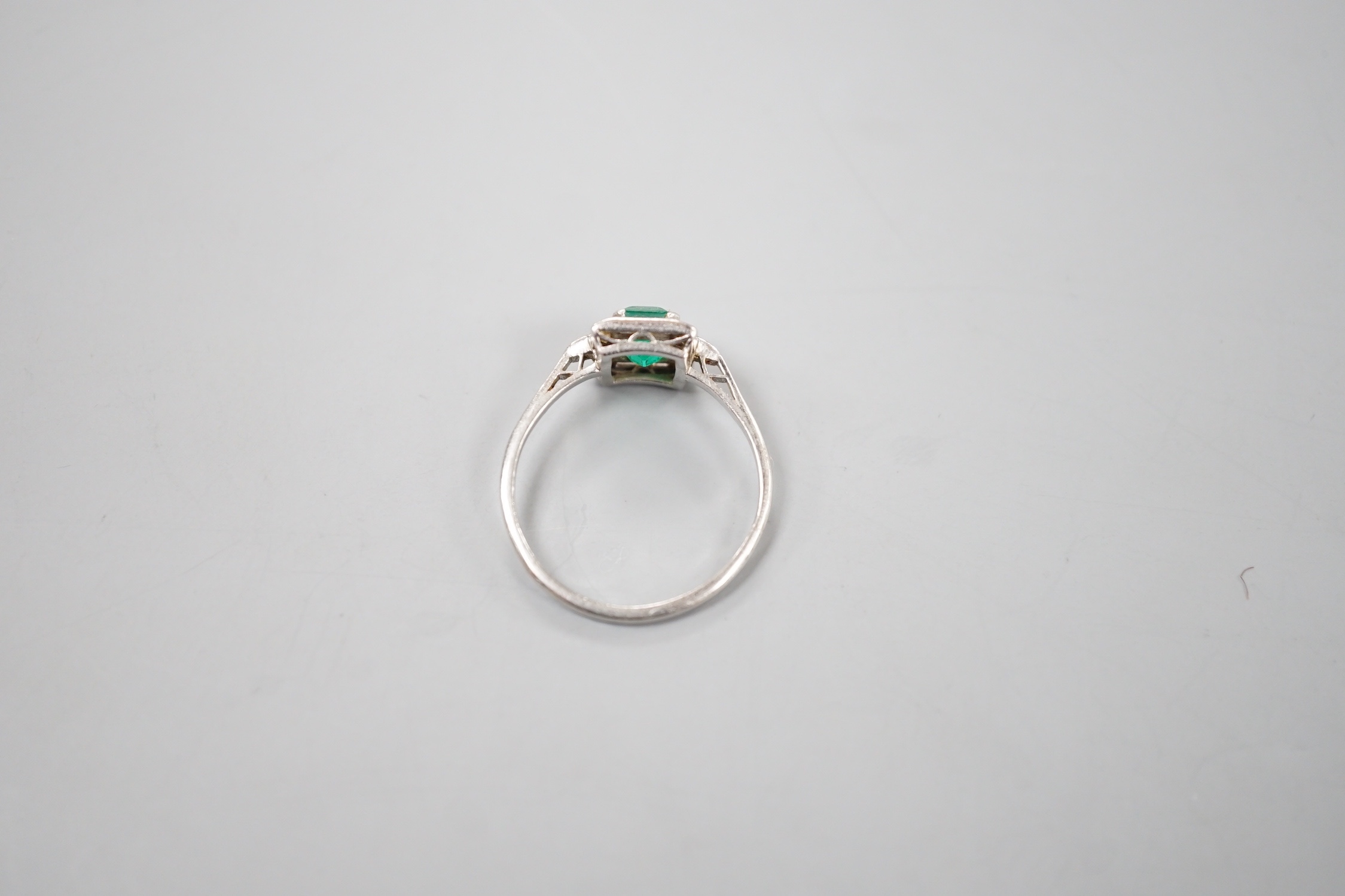 An Art Deco white metal, single stone emerald, baguette and trapeze cut diamond cluster set ring, size R/S, gross 3.5 grams